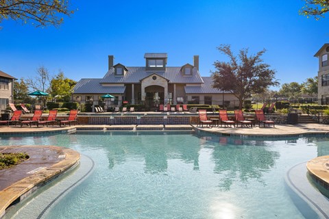 a large pool with chairs and a house in the background